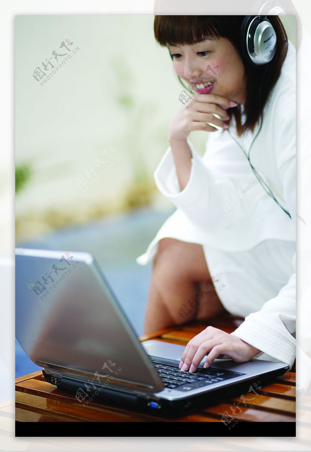 美女坐姿玩电脑听耳机侧面图片