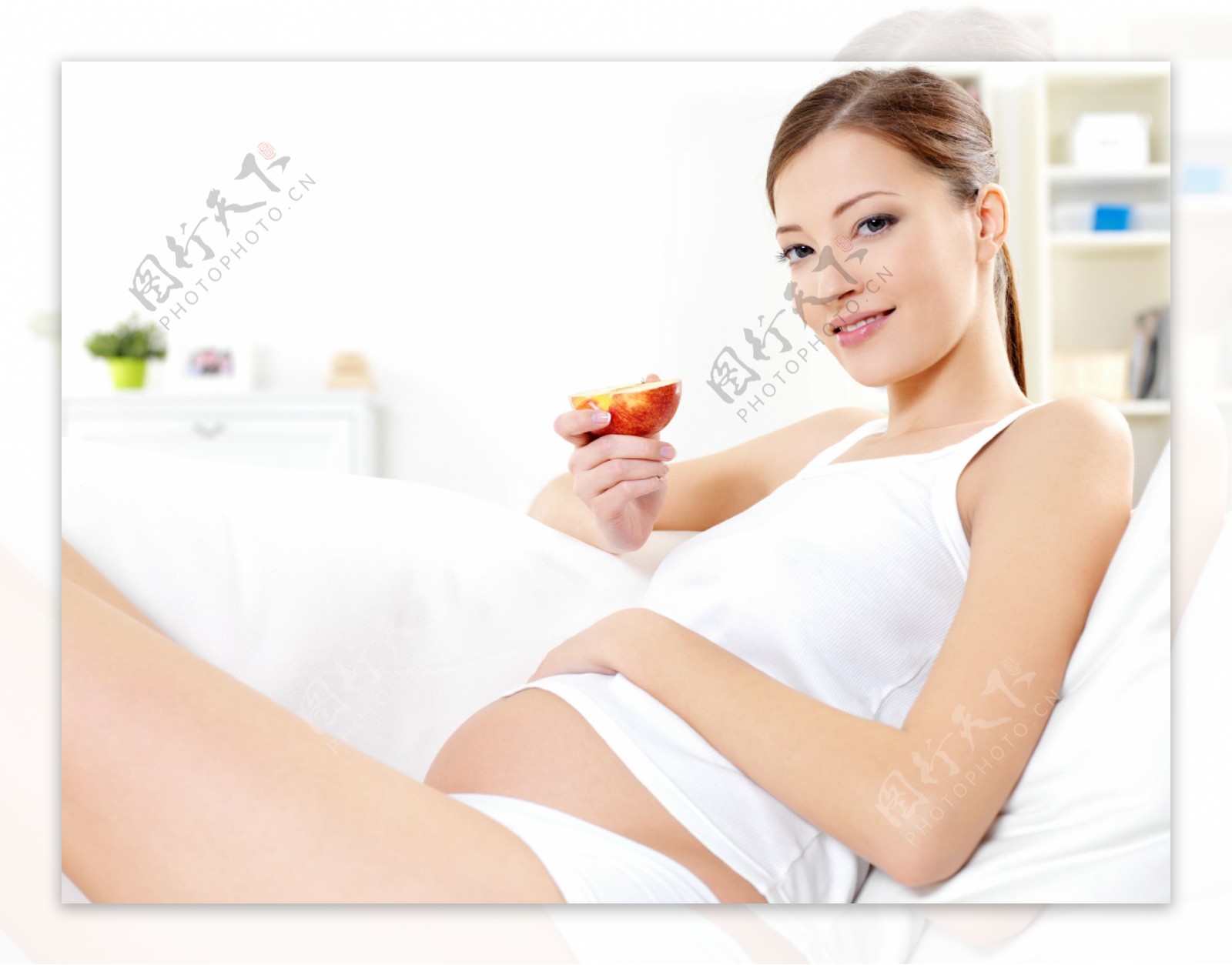 坐在沙发上摸着肚子吃水果的孕妇图片
