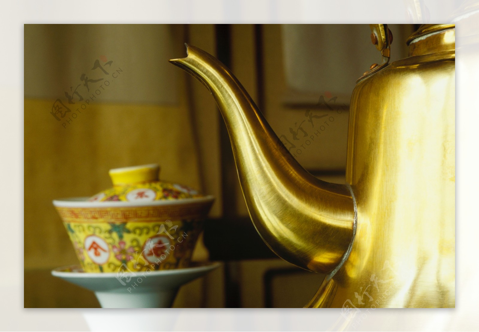 金色水壶旁一个茶杯图片