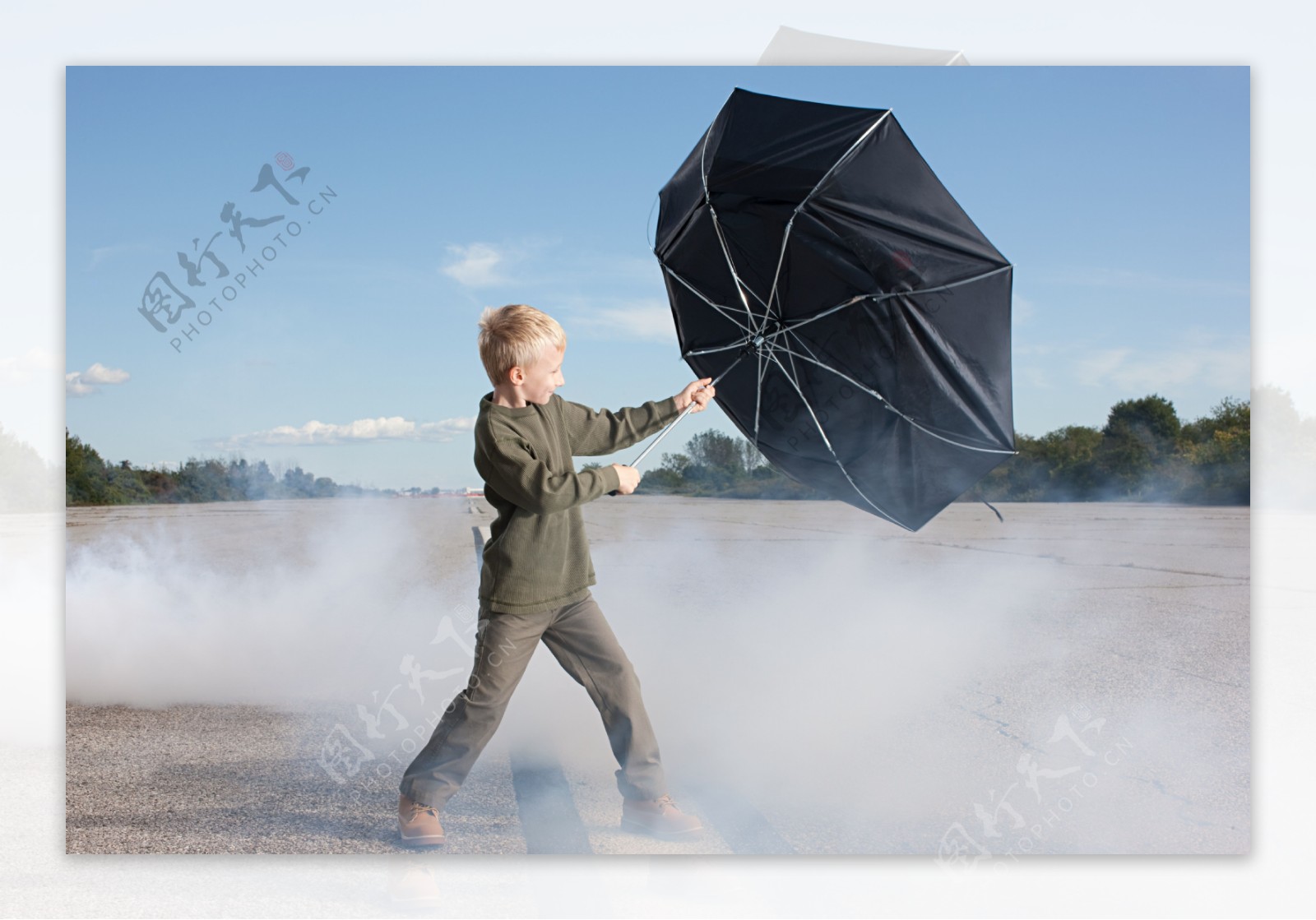 小男孩拿着吹翻的伞图片