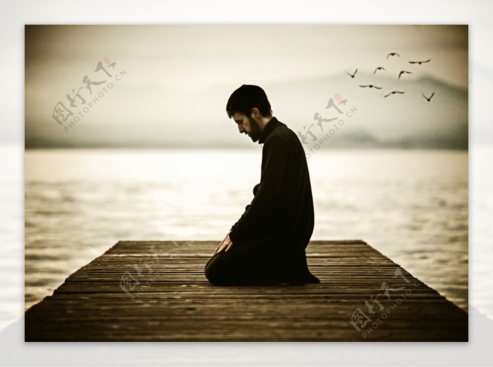 坐在岸边祈祷的男人图片
