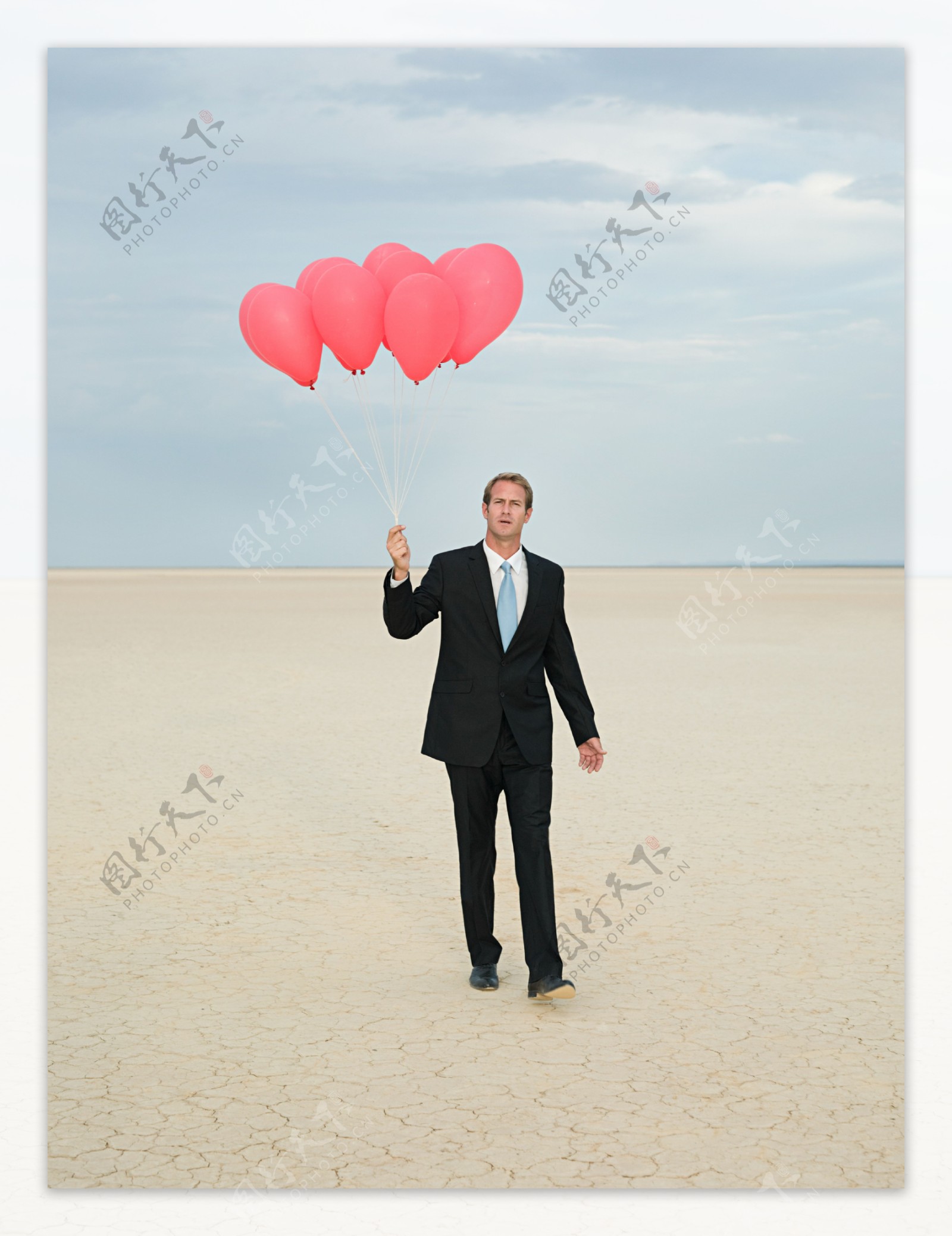 在沙漠中拿着气球奔走的商业男人图片