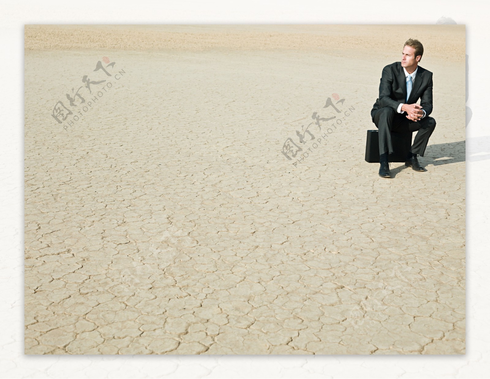 坐在裂缝土地上遥望的外国商业男人图片