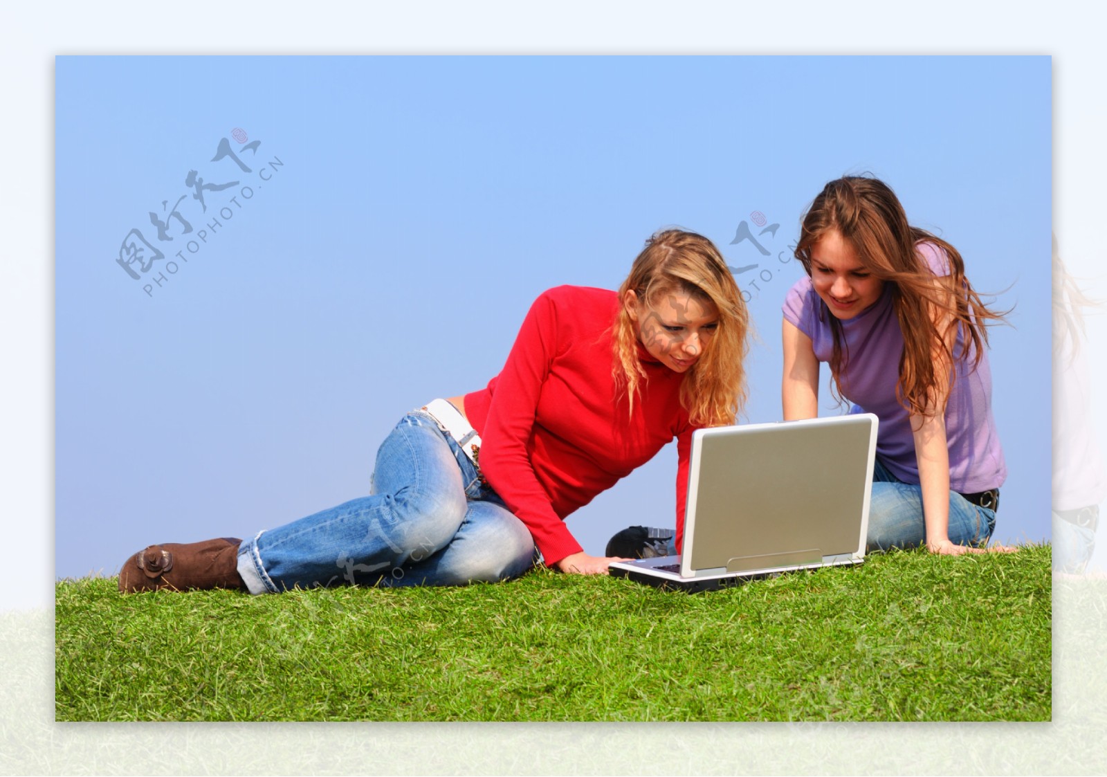 两个坐在草地上上网的女人图片