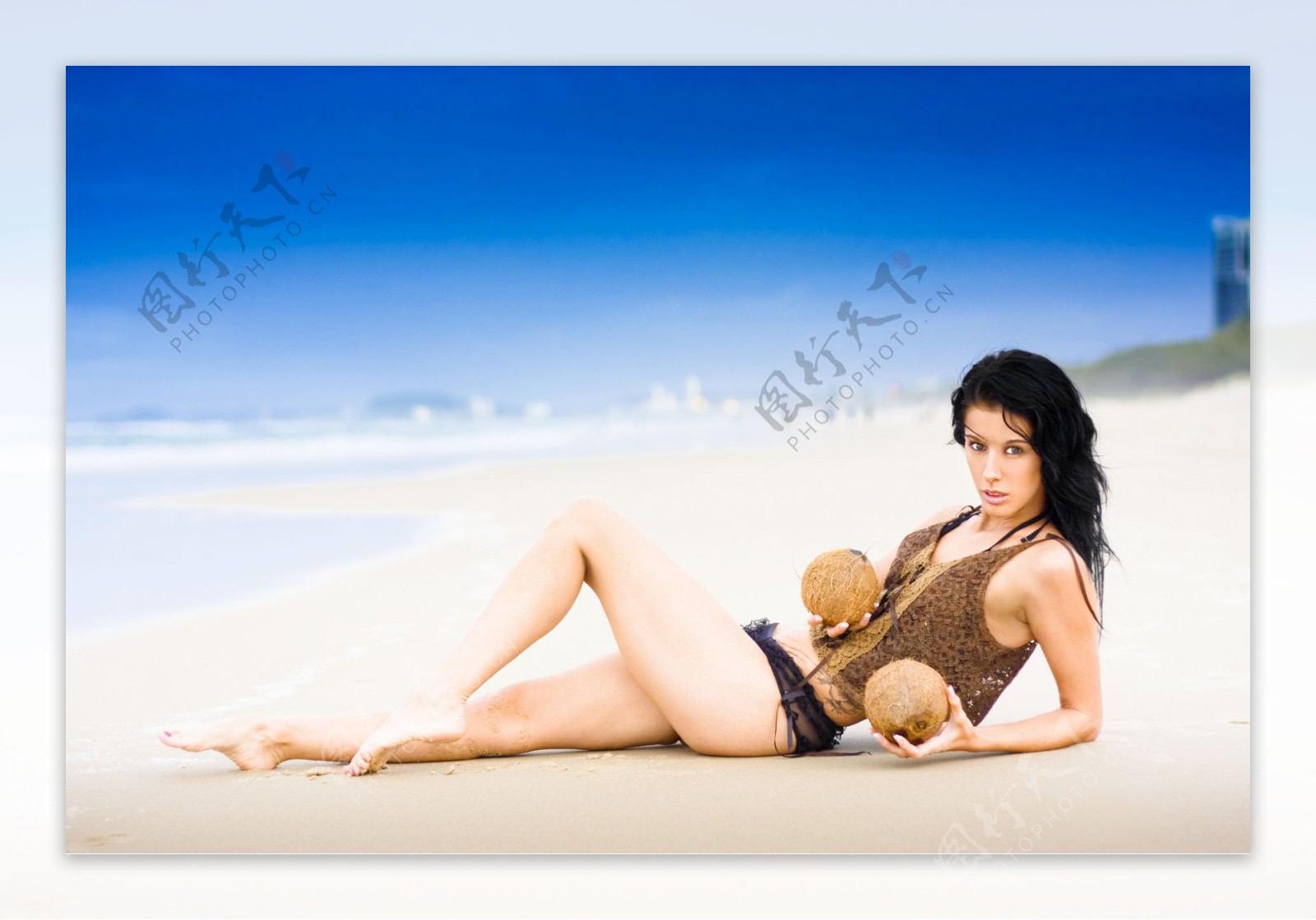 躺在沙滩上拿着椰果的外国美女图片