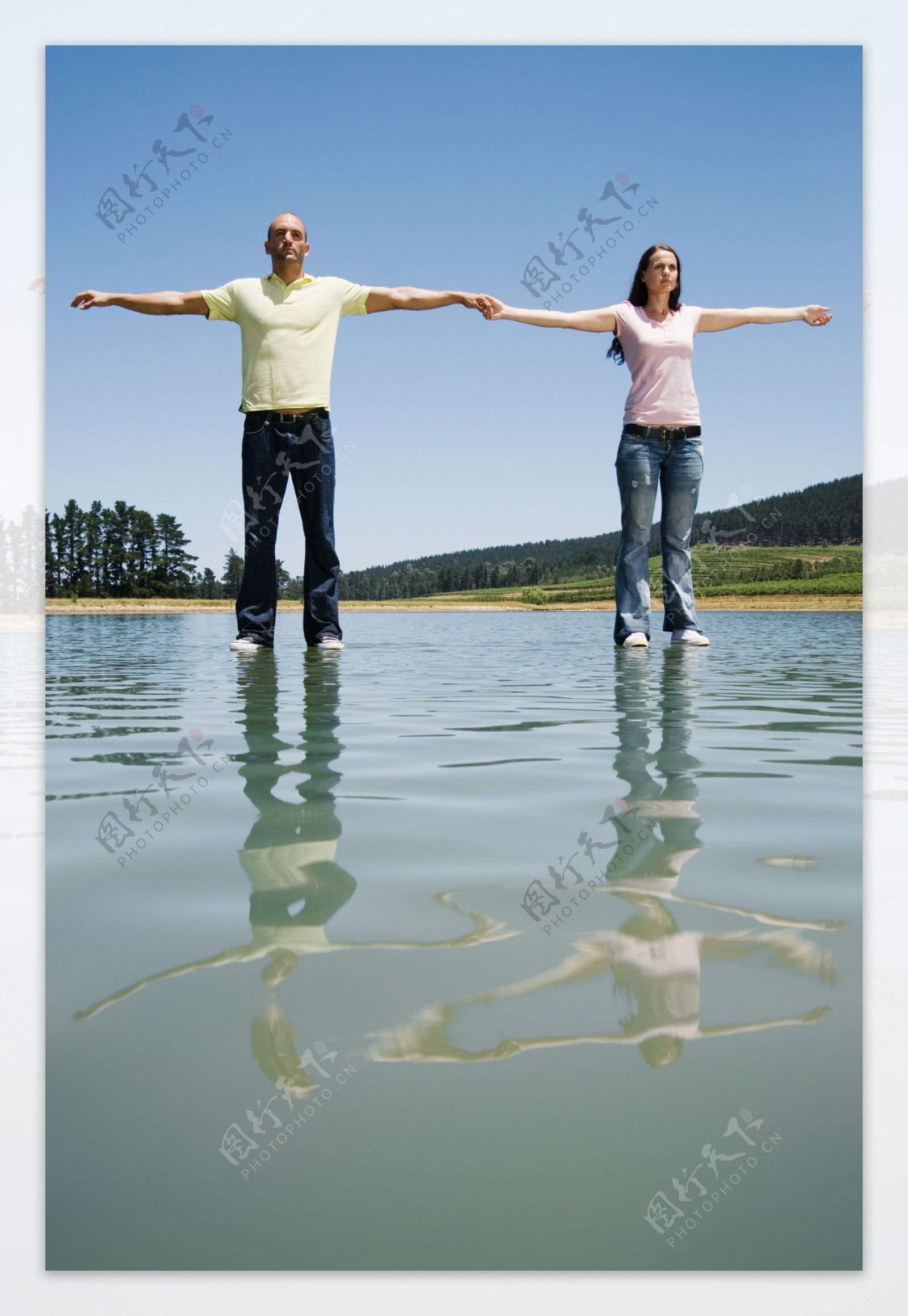 牵手一起站立在水面上的男女图片