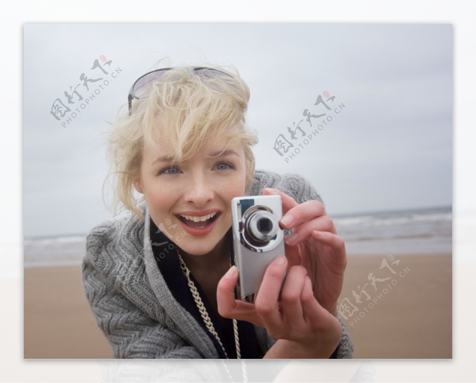 沙滩上正在拍照的女人图片