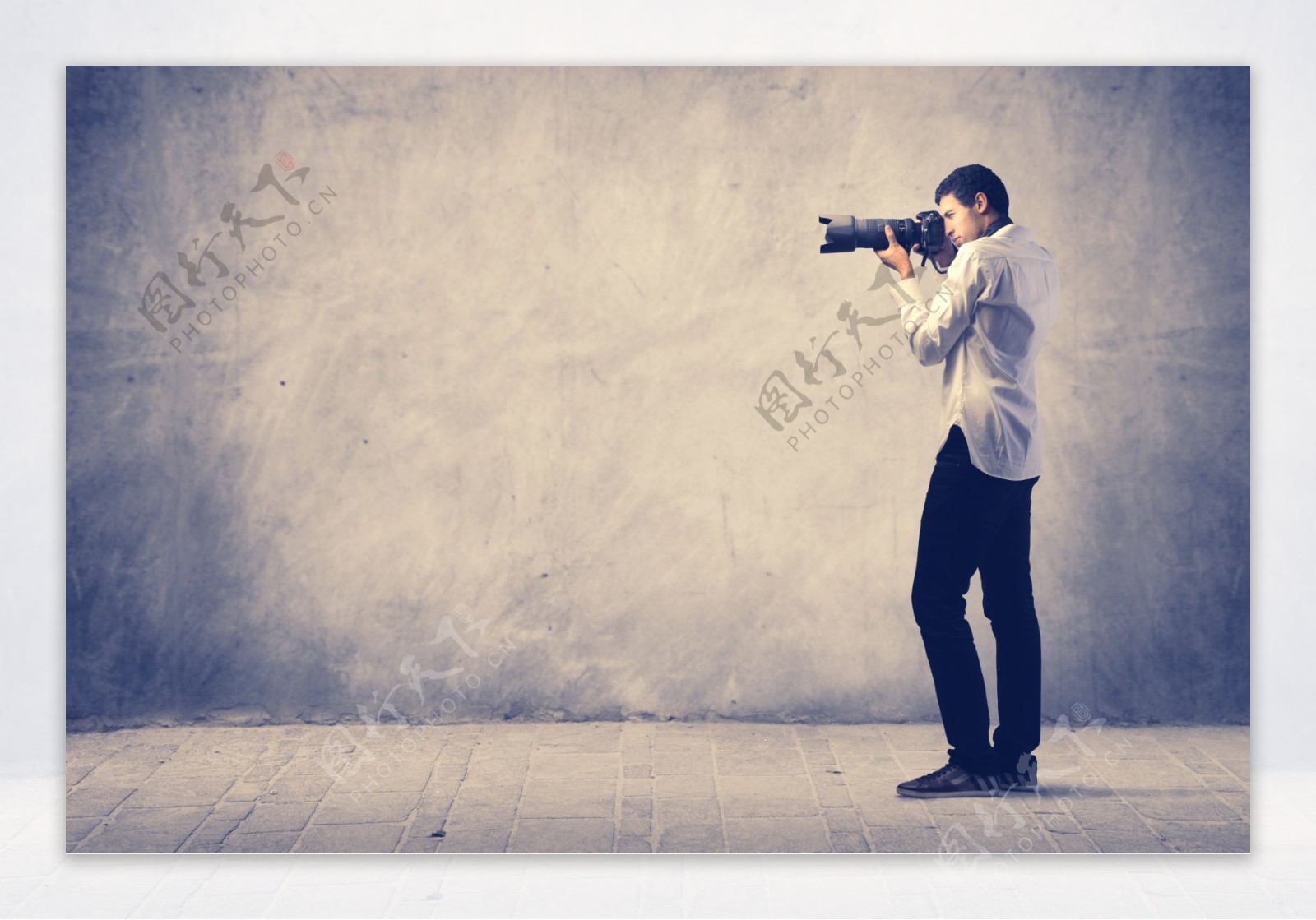 站在墙壁前拍照的摄影师图片