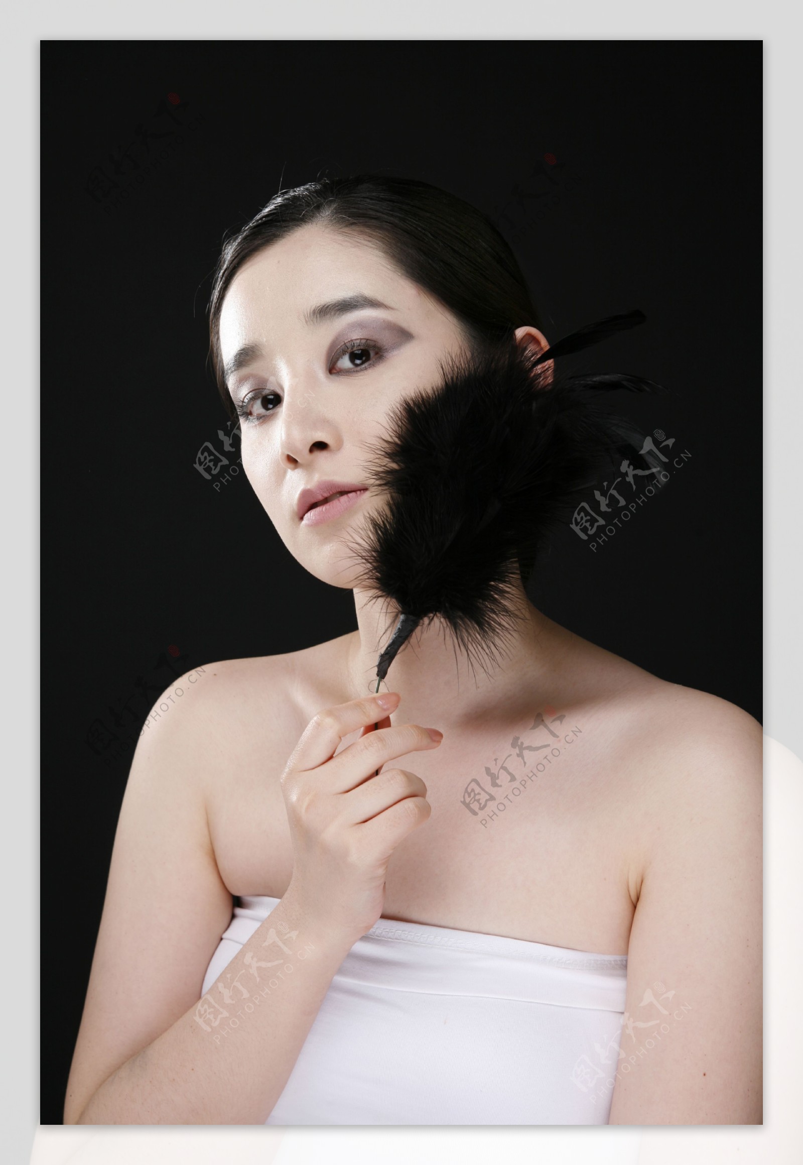 拿着黑色羽毛涂着烟熏妆的女人图片图片