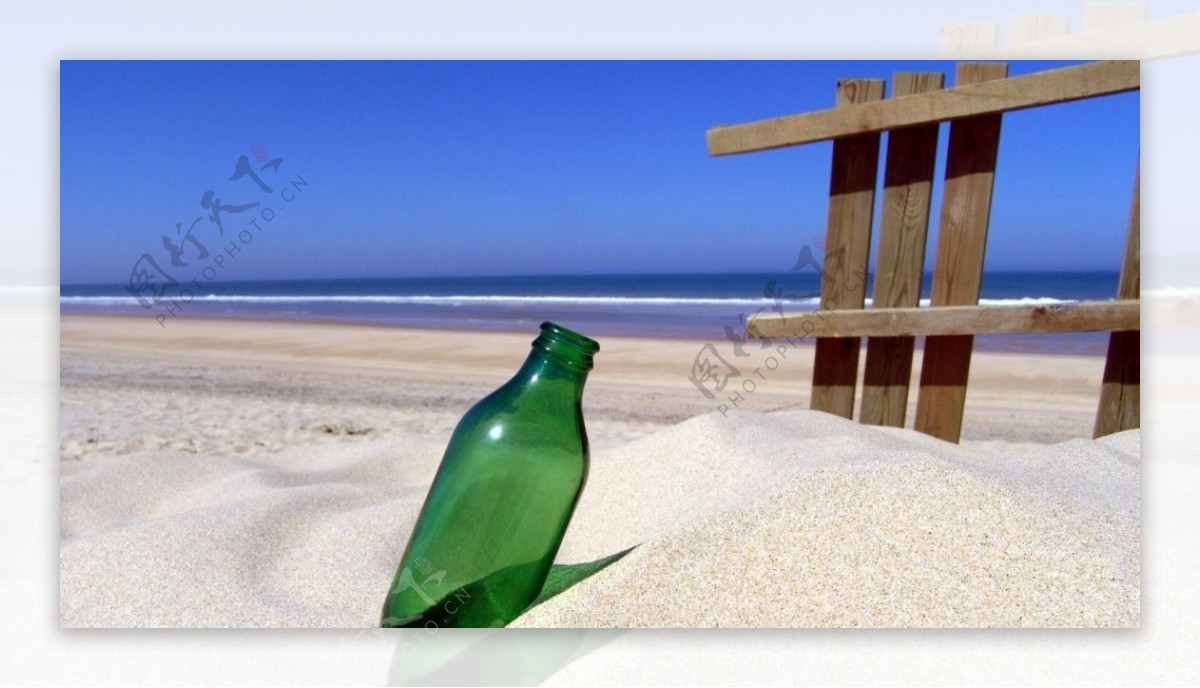 沙滩中的绿色瓶子图片